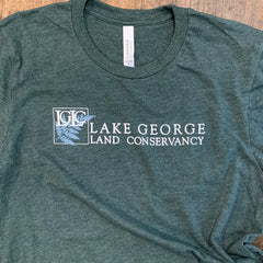 Green t-shirt with 'Lake George Land Conservancy' logo on a wooden surface