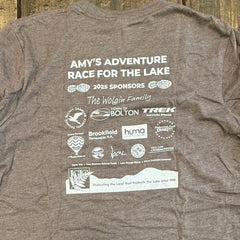 Gray t-shirt with printed text and logos on a wooden surface