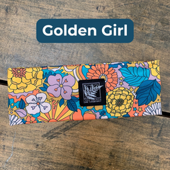 Colorful floral-patterned product with a brand label on a wooden surface, branded 'Golden Girl'.
