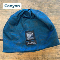 Blue topographic patterned beanie with a black and white LGLC logo embroidered tag on a wooden surface, featuring the style name 'Canyon'.