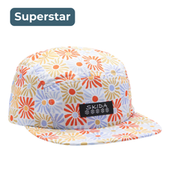 White brim hat with gold, orange and blue radiant sun/floral print pattern, Skida branding on front, labeled "Superstar."