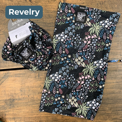 Black fabric with pale pink, green ane blue floral pattern with black and white embroidered labels featuring the LGLC logo and Skida logo. “Revelry”
