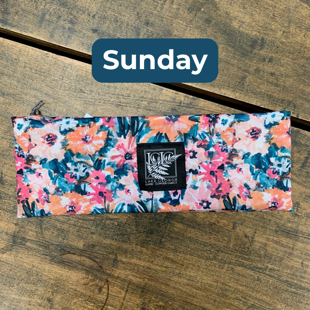 Floral fabric rectangle with a brand label on a wooden surface, labeled 'Sunday'.