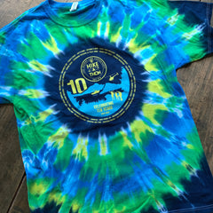 Front of 2022 Tie-Dye Hike-A-Thon Shirt; the anniversary logo is printed in blue and yellow within the navy bullseye, surrounded by the various sites of the Hike-A-Thon written in the outer circle.